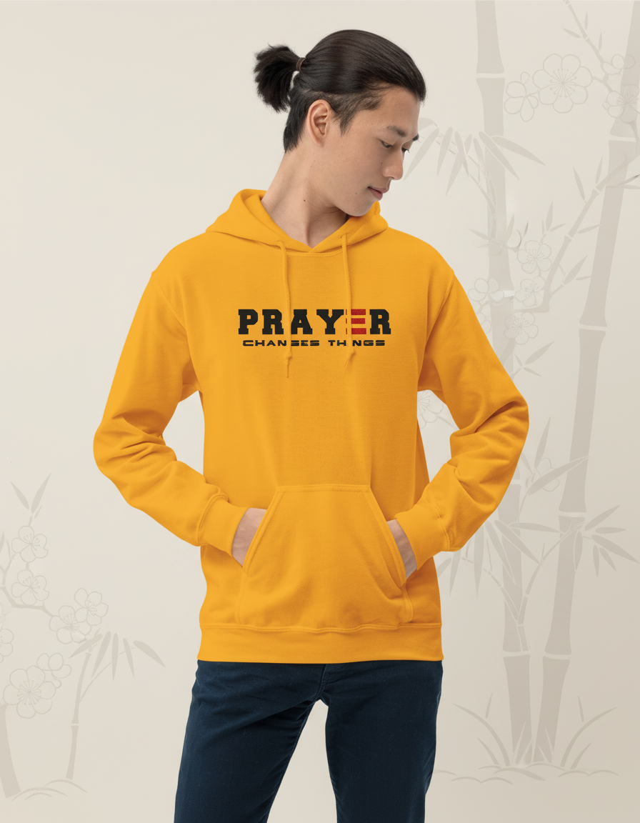 Person wearing a gold hoodie with 'PRAYER CHANGES THINGS' text on a gray background
