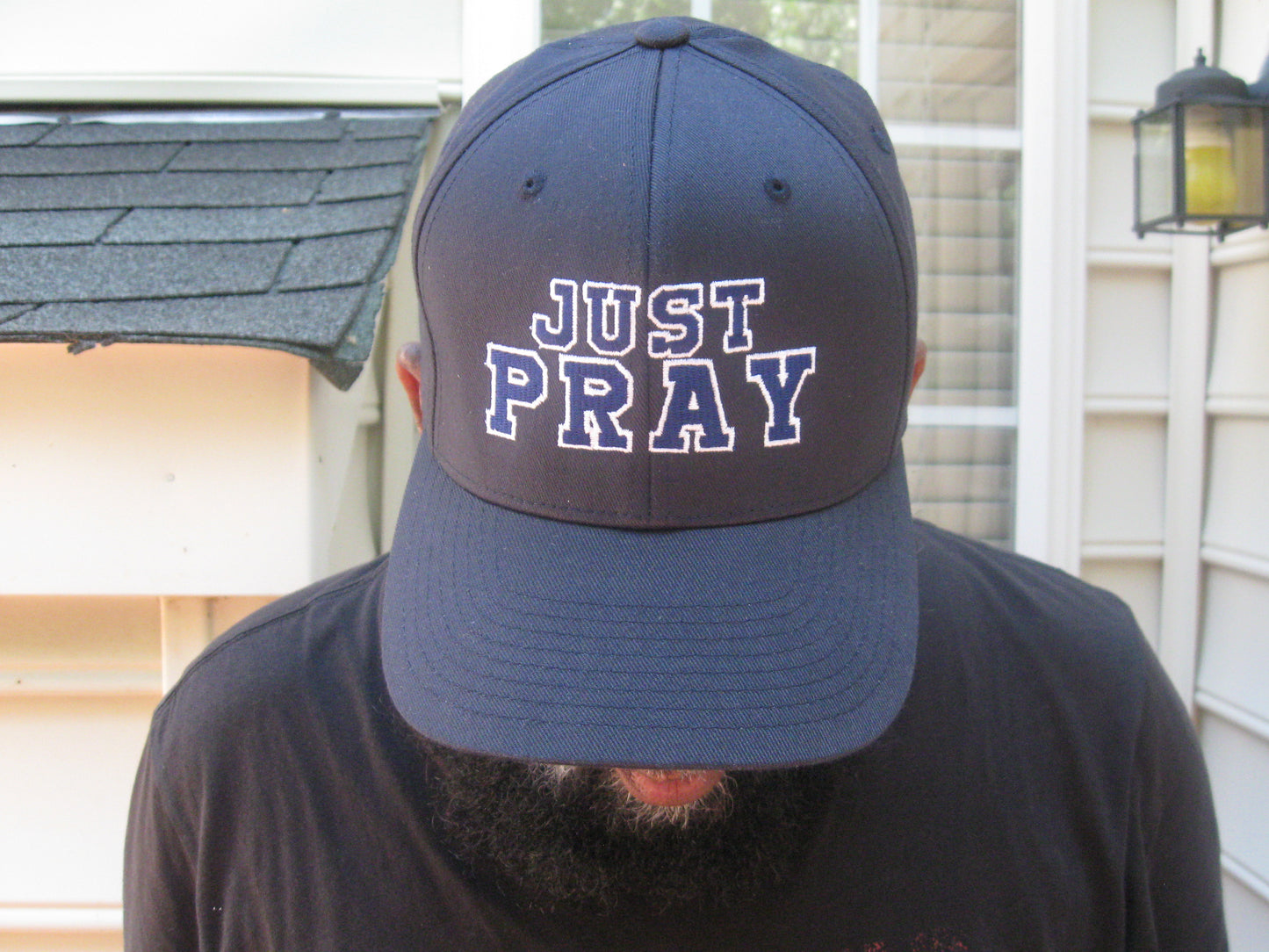 A structured, six-panel twill cap in a blue color featuring the words "Just Pray" embroidered on the front. The cap has a low-profile embroidery area, six vent eyelets for breathability. It is displayed on a neutral background.
