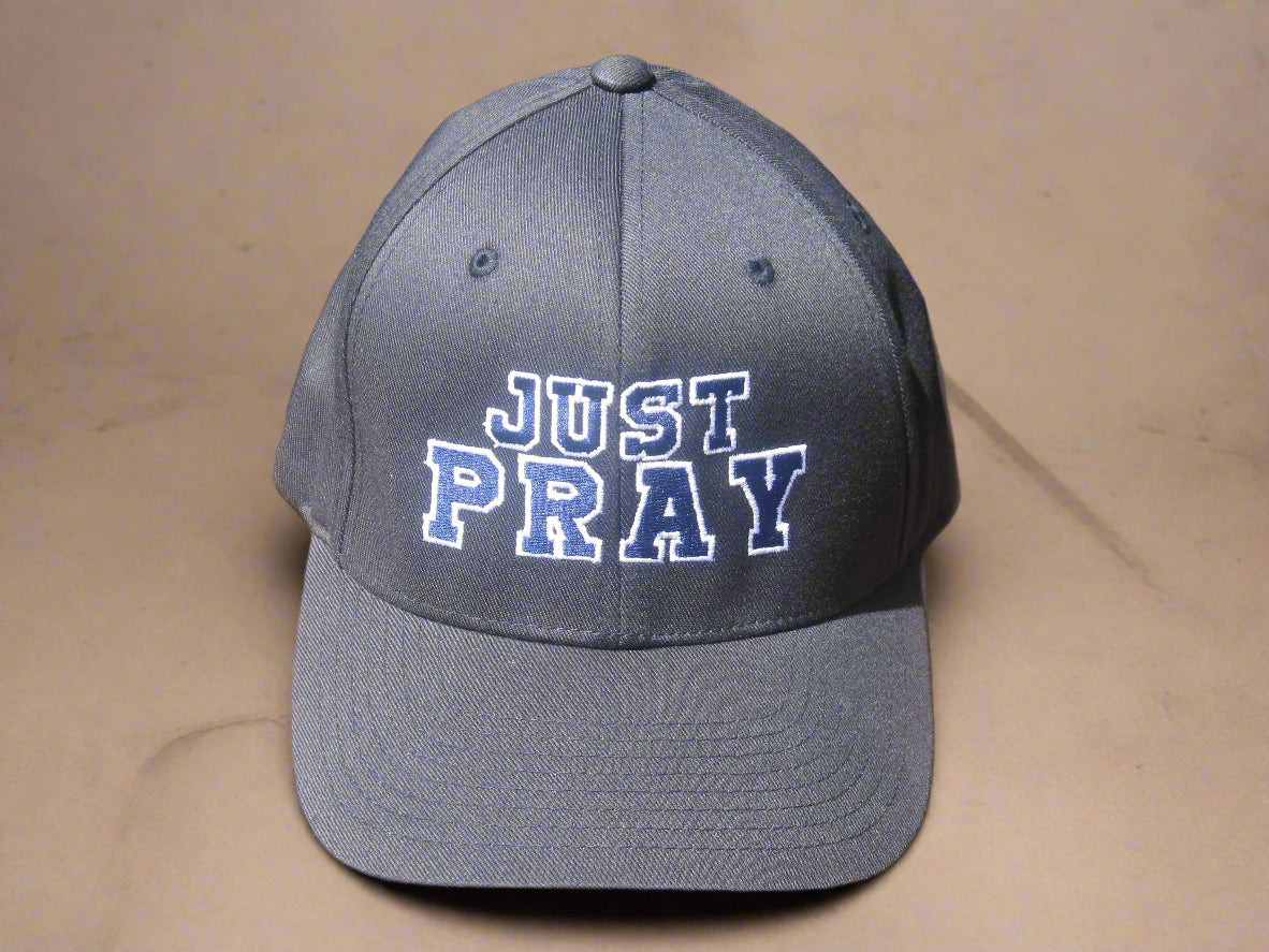 A structured, six-panel twill cap in a blue color featuring the words "Just Pray" embroidered on the front. The cap has a low-profile embroidery area, six vent eyelets for breathability. It is displayed on a neutral background.